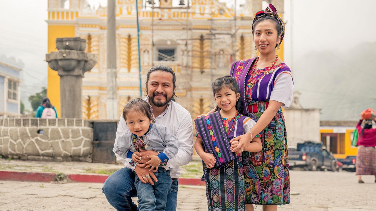 一个穿着传统服装的家庭在危地马拉的一个城镇广场上摆姿势